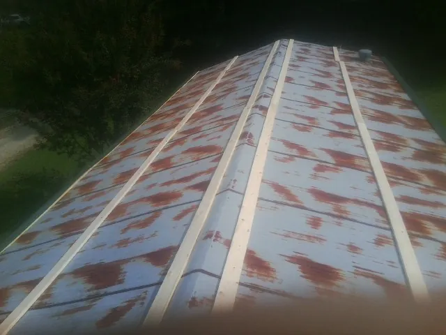 Rusted metal roof panels with new wood purlins before replacement — Storm Damage Roof Repair in Fargo by Roofing Brothers