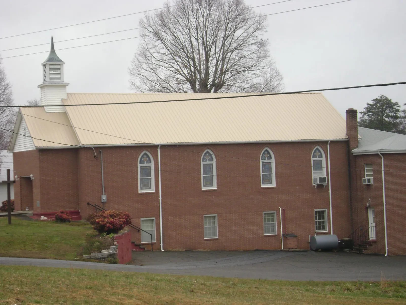 New tan metal roof on a brick church with a white steeple in Fargo