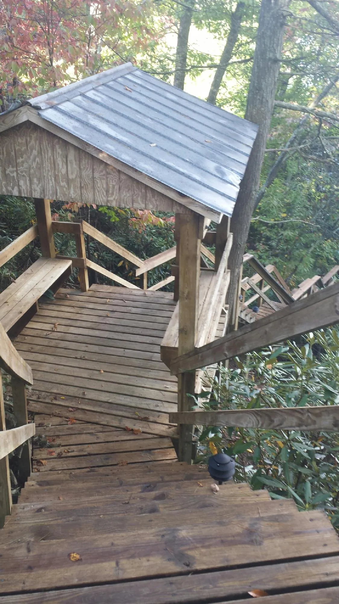Metal roofed shelter over wooden steps on a wooded walkway — Skylight Repair & Installation work by our crew in Fargo