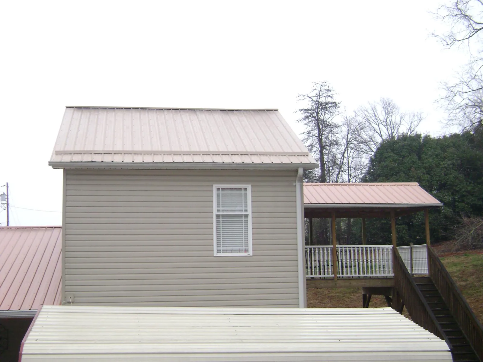Tan metal roofs on a two story addition and attached porch, from a Roof Replacement job in Fargo