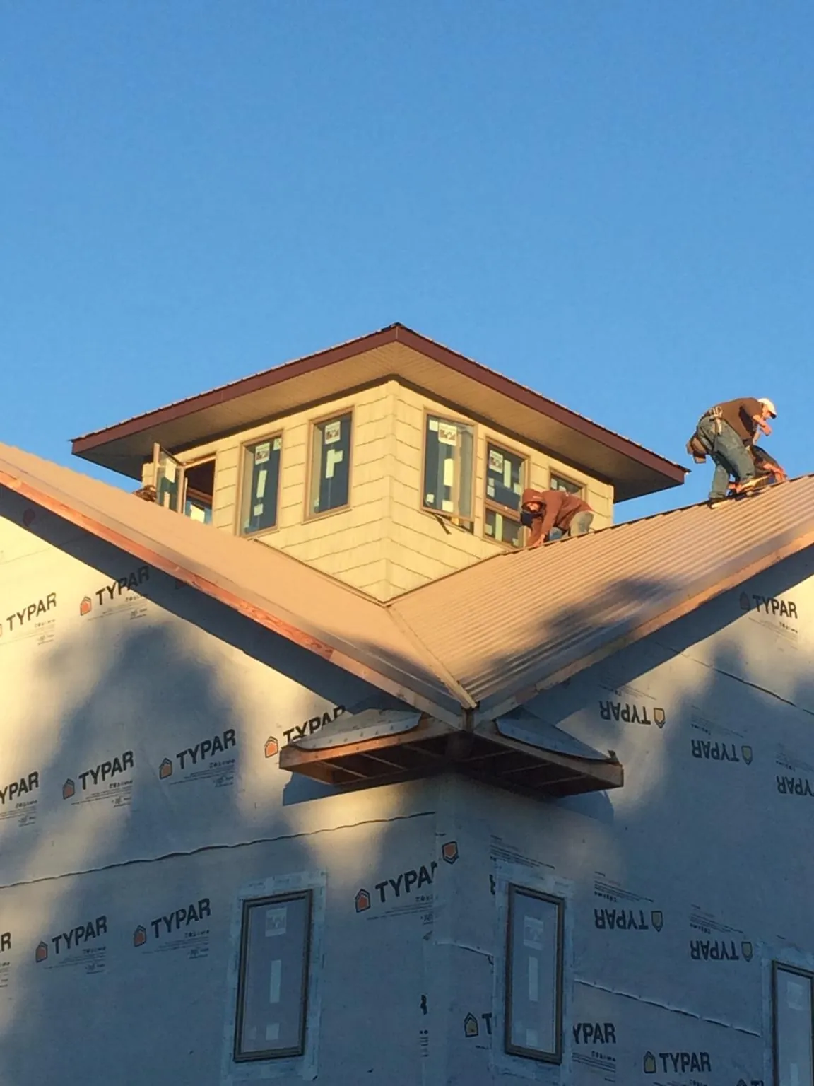 Roofers working around a rooftop cupola on a new metal roof at sunset — Roof Waterproofing in Fargo by Roofing Brothers